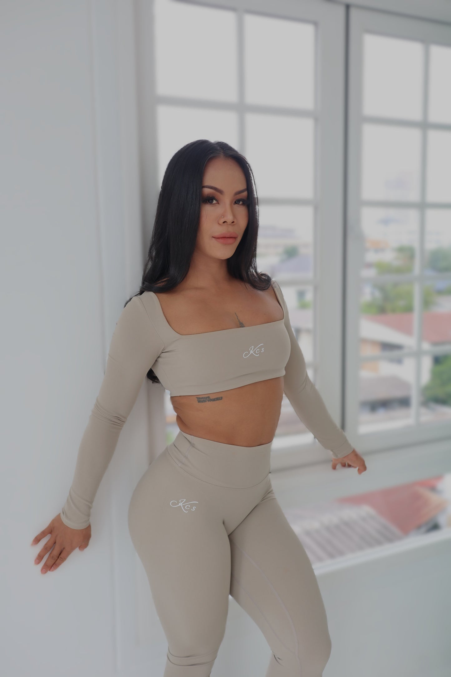 “Model wearing Signature Long-Sleeve Crop Top and Full-Length Leggings in beige, size M – sleek fit with built-in bra pads”